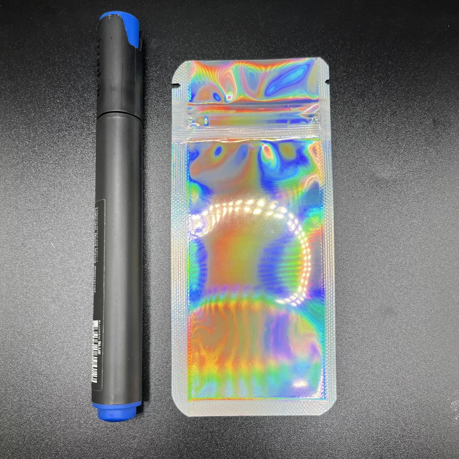 Holographic device mylar bag and pen on a dark background